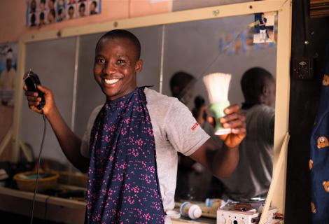 Silas, showing off his hair cut skills at his barbing shop in BAS community