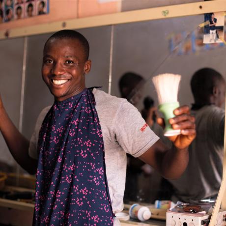 Silas, showing off his hair cut skills at his barbing shop in BAS community